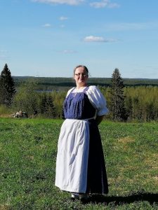 Nainen perinteisessä asussa niityllä.