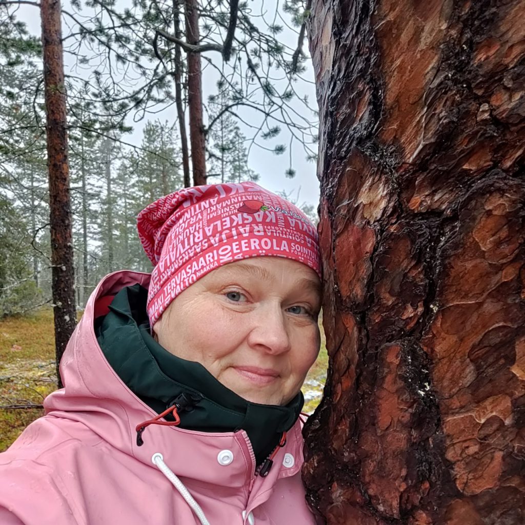 Nainen metsässä puun vieressä