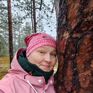 Nainen metsässä puun vieressä